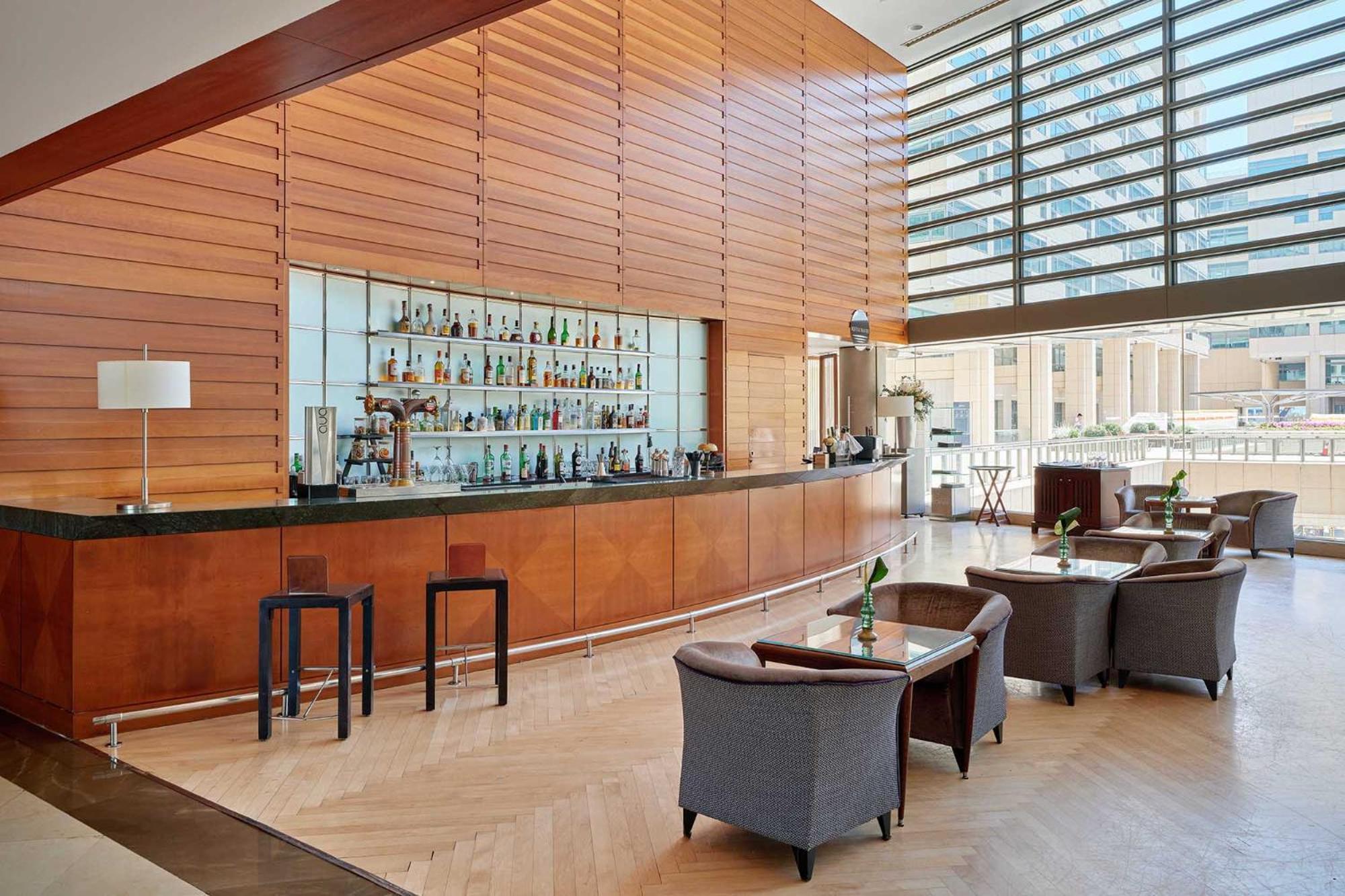 Eurostars Grand Marina Hotel Gl Barcelona Exterior photo The photo shows a modern bar area with a sleek, minimalist design. There is a long, polished bar countertop behind which various bottles of drinks are displayed. The walls feature wooden paneling that creates a warm ambiance, and large windows allow 