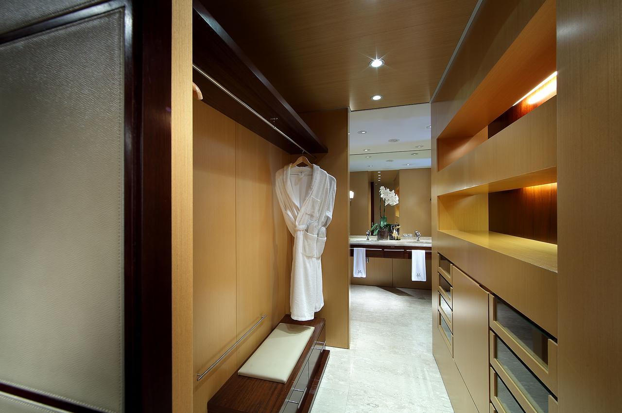 Eurostars Grand Marina Hotel Gl Barcelona Exterior photo The photo depicts a stylish interior space, likely a dressing area or walk-in closet. The walls are finished in warm wood tones, creating a modern and elegant atmosphere. A white robe hangs on a sleek hook, and there is a bench next to it. The area i